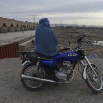 Donna afghana seduta su un motorino